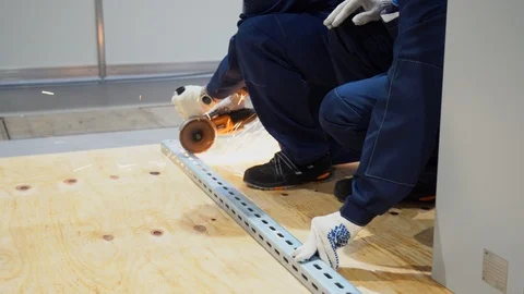 One builder saws with tool grinder long square metal pipe lying on floor  Stock-Footage 126356253