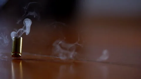 One bullet shell casing falling to the wooden surface in slow motion. Fired Stock Footage 334021346