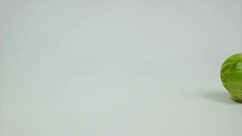 One cabbage comes in the middle of the frame, spins and leaves the frame. StopMo Stock-Footage 84143221