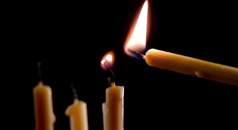 One Candle Being Lit from the Flame of Another Against Dark Background 4K Stock-Footage 332157852