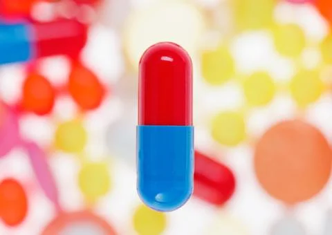 One capsule (pill) macro view on blurred multicolored drugs background, medic Stock-Fotos