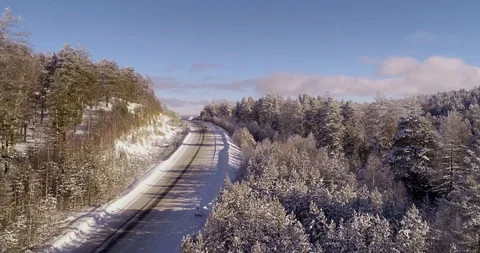 One car rides on an empty road in the middle of a frozen and snowy forest Stock Footage 104483159