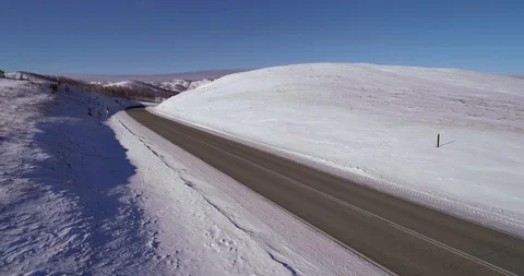 One car rides on an empty snowy road in the mountains Stock Footage 104471999