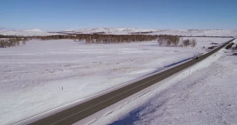 One car rides on an empty snowy road in the mountains Stock Footage 104472250