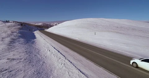 One car rides on an empty snowy road in the mountains Stock Footage 104472251