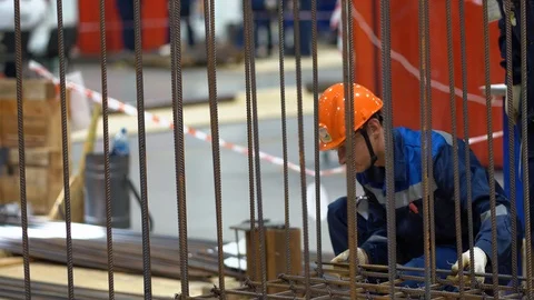 One Caucasian worker guy makes frame of rebar, binds horizontal, vertical bars Stock Footage 126357567