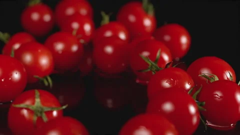 One cherry tomato falls among a large number of tomatoes. A juicy cherry tomato Stock Footage 135959963