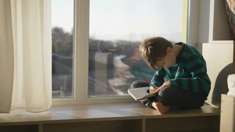 One child sit at window and write on notebook, creative, imagination, leisure Stock Footage 150725016