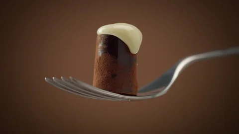 One chocolate candy on fork covered by white cream, slowly falling down Video stock 86286375