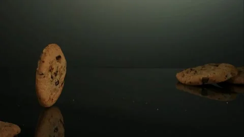 One chocolate chip cookie rolls and wobbles across a dark reflective. Stock Footage 326750668