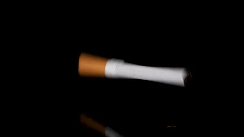 One cigarette falling and bouncing on black reflective surface in slow motion. Stock Footage 146948629