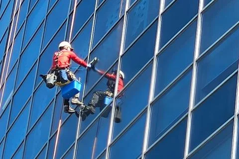 One climber washes the outside windows of a skyscraper at a great height. P.. Stock Photos