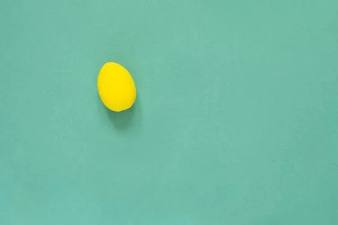 One colored yellow painted egg on green background Easter card with empty spa Stock Photos