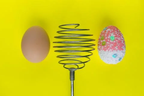 One colorful decorated easter egg and one real egg and whisk Stock Photos