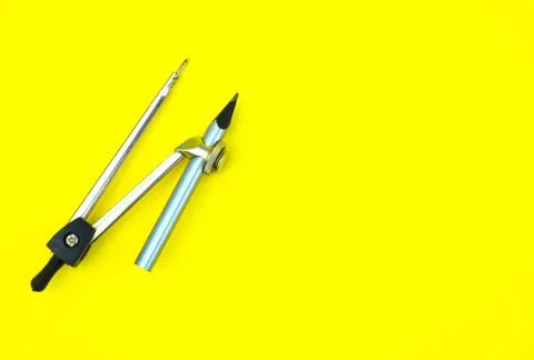 One compass attached to a silver color wood pencil crayon on a yellow backgro Stock Photos