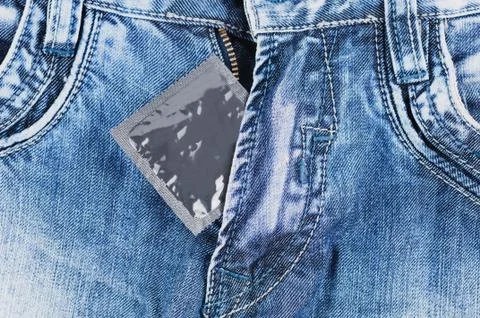 One condom in silver package on blue jeans Stock Photos