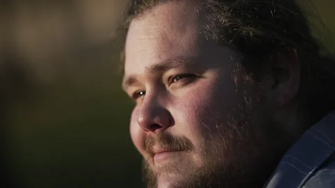 One contemplative overweight young man smiling outdoors during golden hour .. Stock Footage 244211153