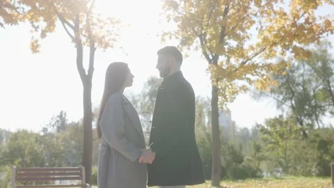 One couple stepping closer to hold hands in a sunny autumn park cinematic style. Stock-Footage 332763771