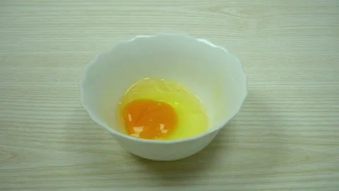 One cracking egg falls into white ceramic bowl. Slow motion video Stock Footage 233518630