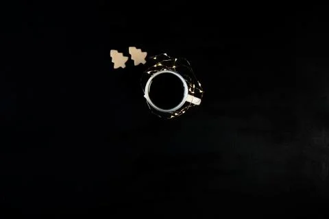 One cup with coffee on black table with christmas lights and cookies . Photog Stock Photos