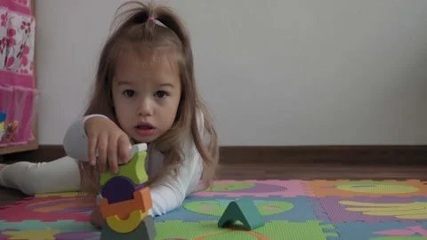 One cute small kid build wooden pyramid sitting on floor colored soft mat puzzle Stock Footage 142060579