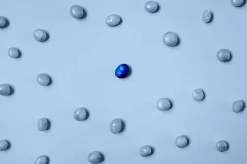 One dark blue candy bean among light blue ones Stock Photos