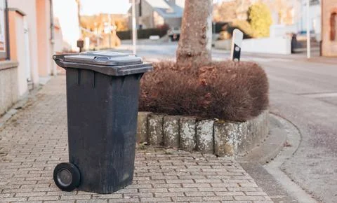One dirty plastic garbage container standing on a city street. Stock Photos