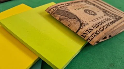 One dollar bill resting on bright yellow sticky note pads Stock Photos