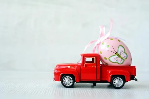 One Easter egg on a small car on a grey background. Copy space. Foto stock