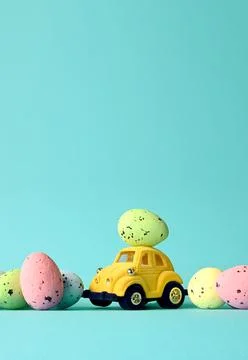 One Easter egg on a small car on a blue background. Copy space. Stock Photos