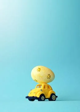 One Easter egg on a small car on a blue background. Copy space. Stock Photos