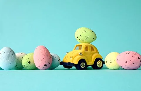 One Easter egg on a small car on a blue background. Copy space. Stock Photos