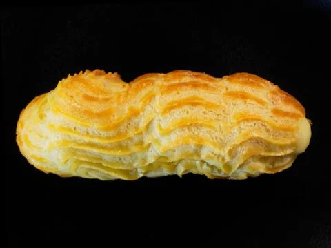 One eclair on a black background. Cake close-up, top view. Foto stock