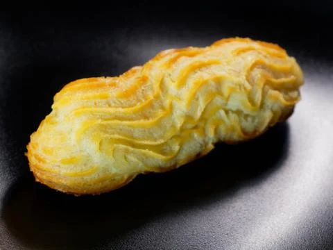 One eclair on a black background. Delicious homemade cakes. Stock Photos