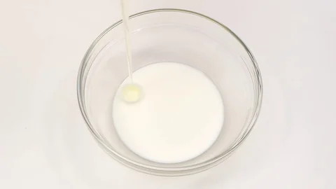 One egg falls in plate with milk. Slow motion, closeup Stock Footage 76147573