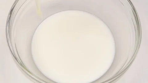One egg falls in plate with milk. Closeup, slow motion Vidéo 76147649