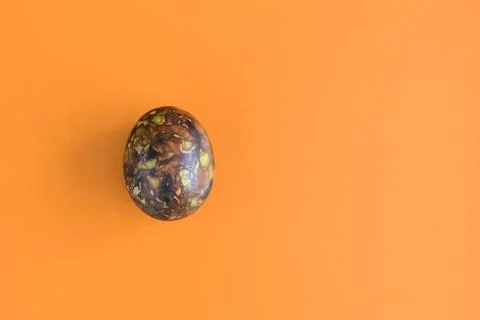 One egg, painted in brown colors, on orange background. Minimalism concept Stock Photos