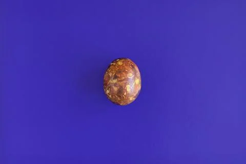 One egg, painted in brown colors, on blue background. Minimalism concept Stock Photos