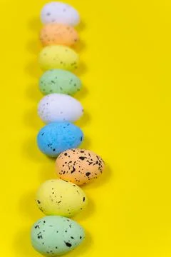 One egg stood out from a row of brightly colored Easter eggs against a yellow Stock Photos