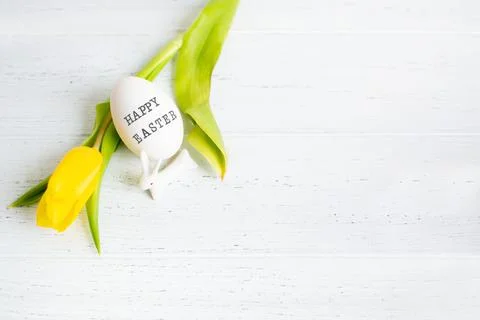 One egg with text Happy Easter and yellow tulip and white small ceramic bunny 스톡 사진