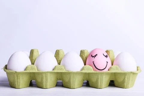 One egg in the tray is different smile, copy space. Happy Easter concept gree Stock Photos