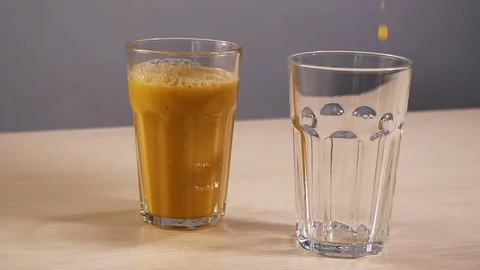 One empty glass filled refresh orange juice slowmotion white background closeup Stock Footage 113073941