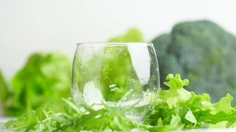 One empty glass with water drops on the green vegetables background, rotati.. Stock Footage 258287195