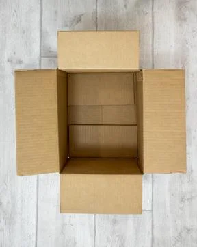 One empty open cardboard box on white wood laminate Stock Photos