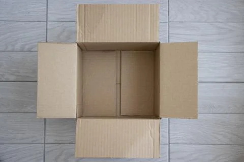 One empty open cardboard box on the wood floor Stock Photos
