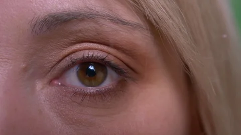 One eye portrait of middle-aged blonde short-haired model watches calmly into Video stock 108681493