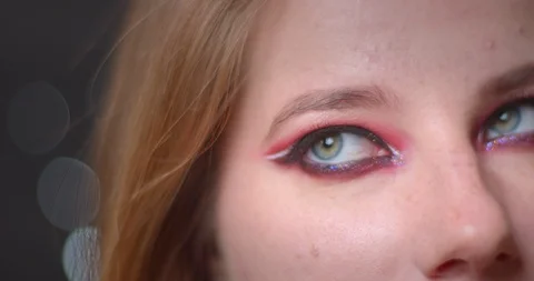 One eye shoot of blonde model with bright make-up watching downwards on bokeh Video stock 108846054