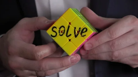 On one face of the Rubik's cube is written "solve". Businessman hands solving Stock Footage 92541226
