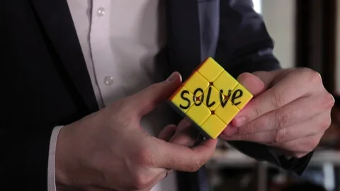 On one face of the Rubik's cube is written "solve". Businessman hands in the Stock Footage 92542737