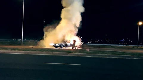 One firefighter dousing the burning vehicle with foam at the scene of the car cr Video stock 101023968